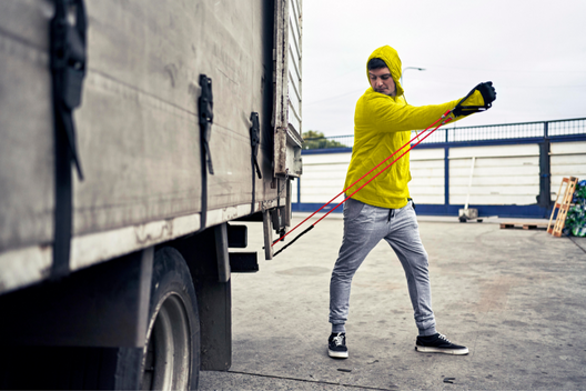 truck driver working out by truck with resistance band